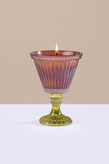 brown glass candle holder with a lit candle on a beige background